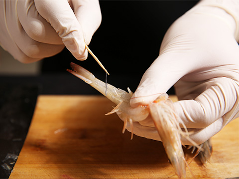 用剪刀將蝦腔、蝦須剪掉，用刀從蝦腹部片一刀并剔去蝦線(xiàn)；
